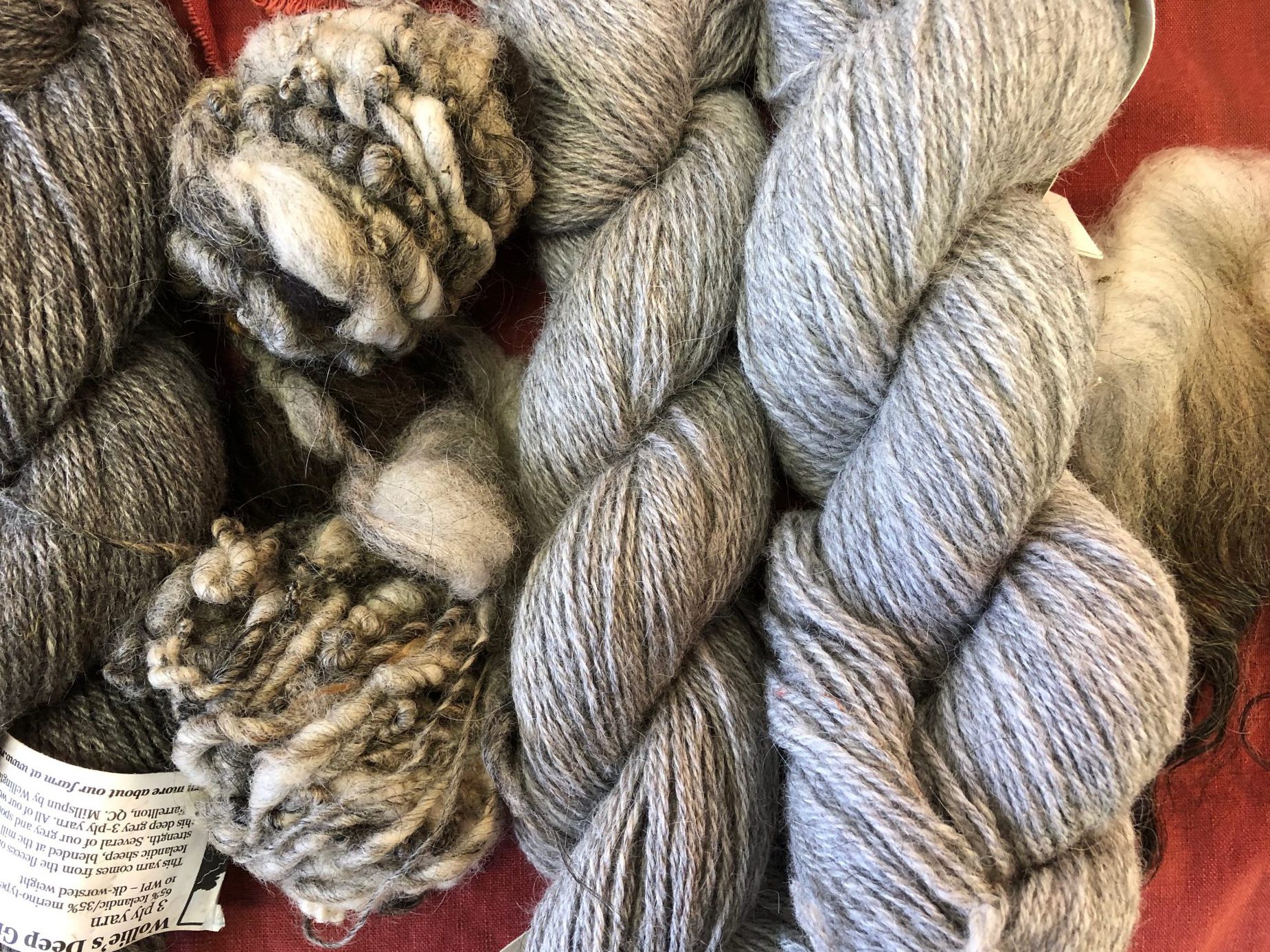 A collection of wool in natural colours, in skeins and hand spun balls, and a bit of unspun fleece